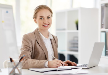 Pretty young accountant sitting by desk, planning work and browsing in the net